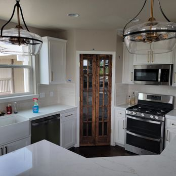 Remodeled kitchen with quartz counters, farmhouse sink, and reclaimed wood pantry doors