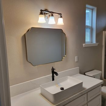Remodeled bathroom with vessel sink, quartz vanity, and gold-framed mirror