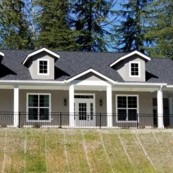Newly built country home with dormers, white columns, and wraparound porch